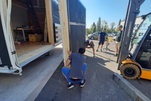 Zwei Mitarbeiter der Firma DPM halten eine Wand und bauen sie mit Hilfe eines Staplers in den Prüfstand ein.