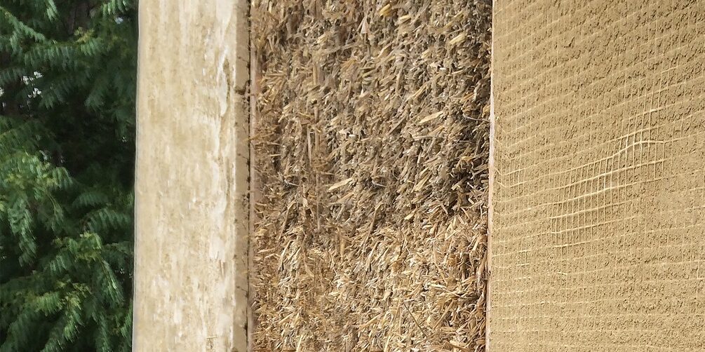 A wall with three different superstructures (left: clay plaster; center: straw; right: clay slab). In the background you can see a tree.